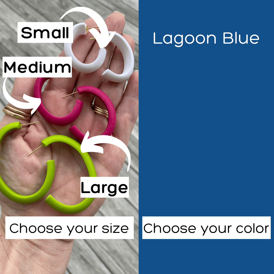 vibrant blue polymer clay hoop earrings with a smooth matte texture, hanging from a transparent stand with greenery in the background