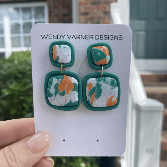 Close-up of colorful square drop polymer clay earrings with abstract design in green and orange