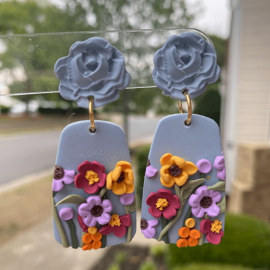 Handmade floral polymer clay earrings with blue rose studs and intricate flower garden design