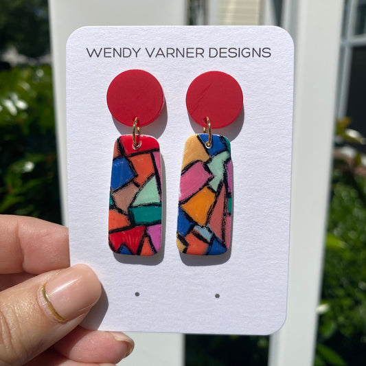 Hand-painted polymer clay stained glass mosaic dangle earrings with red circle studs on a Wendy Varner Designs earring card, handmade in Charlotte NC