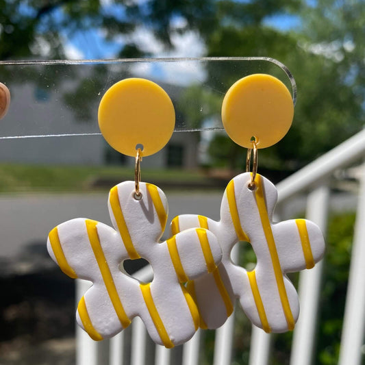Handmade retro flower earrings in orange and white polymer clay, shown from the front hanging on display.