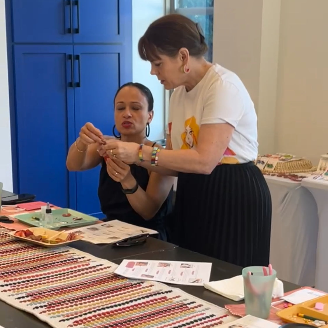 Workshop instructor demonstrating earring assembly at a clay earring workshop, with tools and materials on the table.