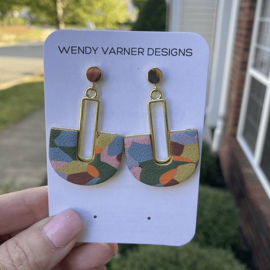 Colorful hand-painted arch earrings with gold detail photographed in natural outdoor li