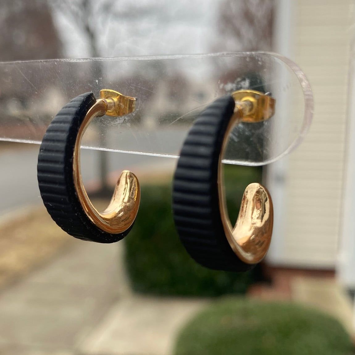 Side angle of black and gold textured polymer clay hoop earrings