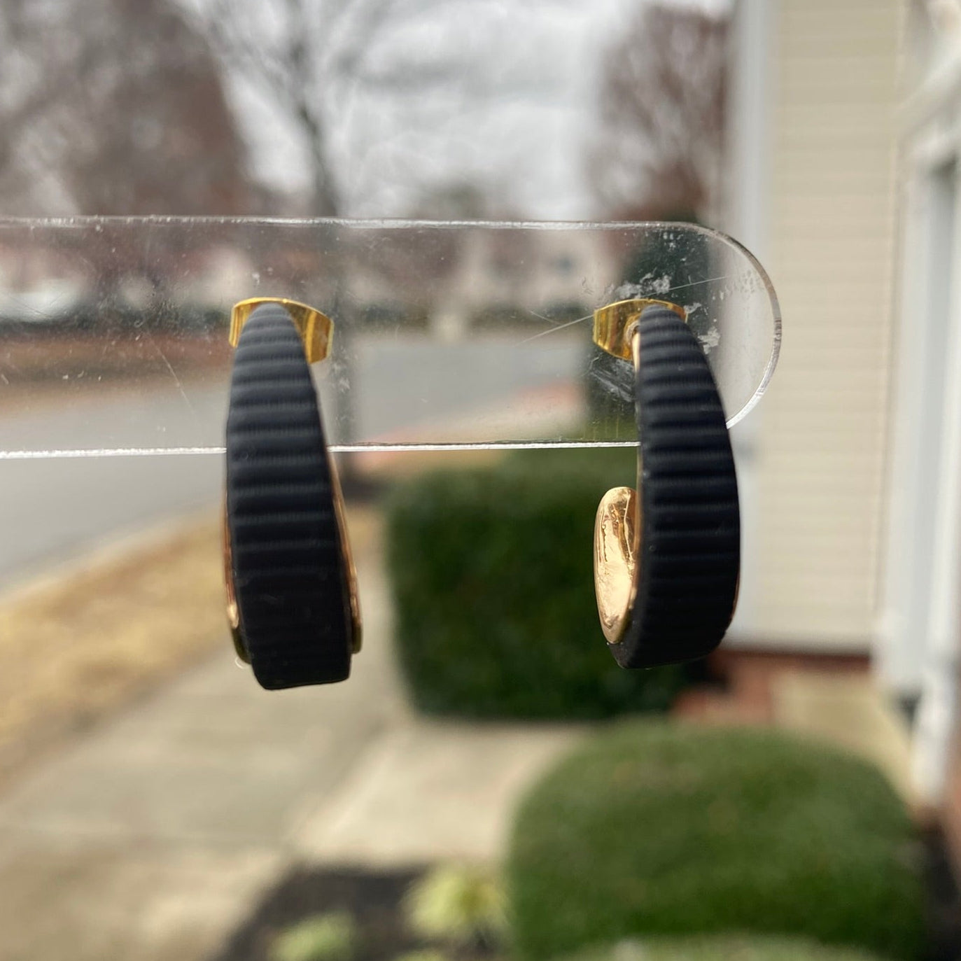 Close-up photo of black polymer clay hoops with gold inner curve, lightweight handmade earrings