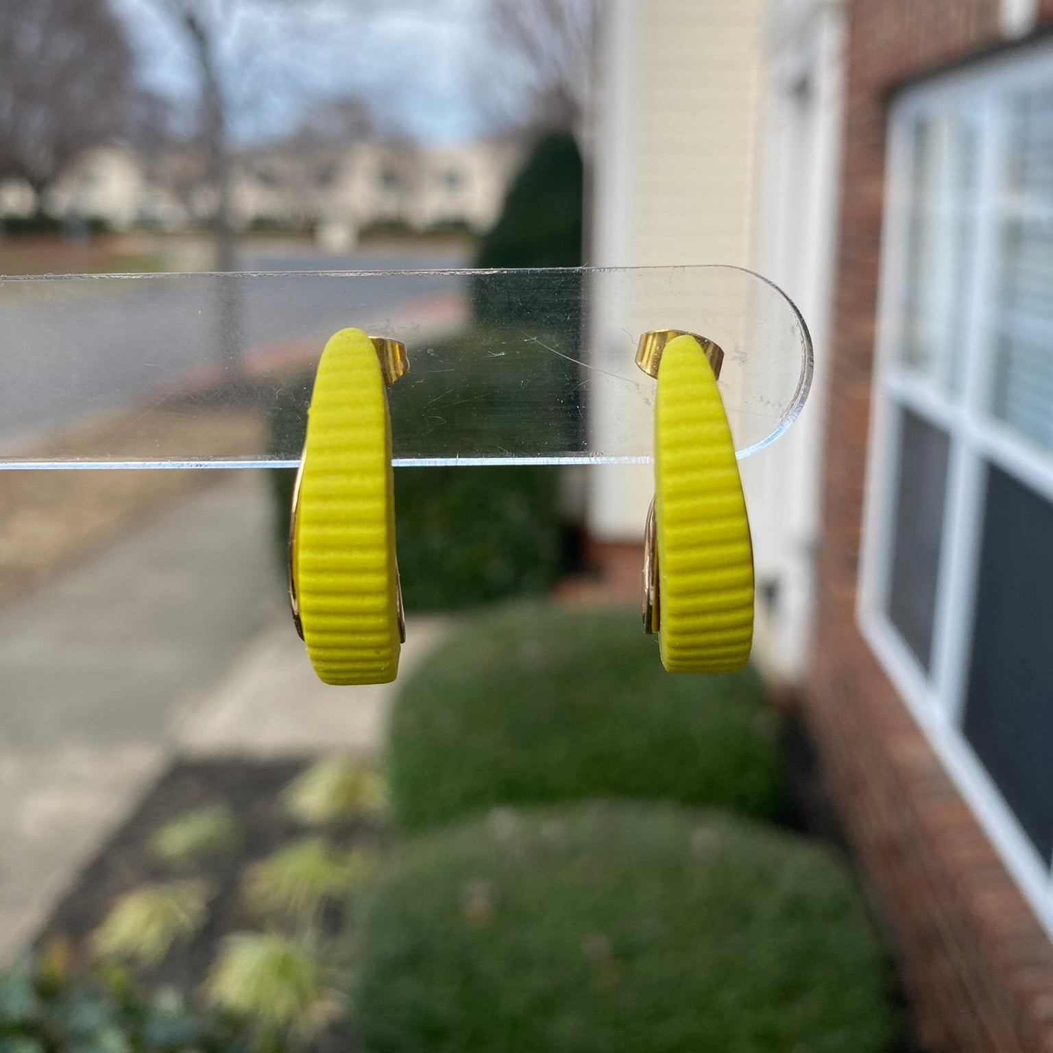 Citron green and gold polymer clay hoop earrings displayed outdoors on clear stand, handmade by Wendy Varner Designs 
