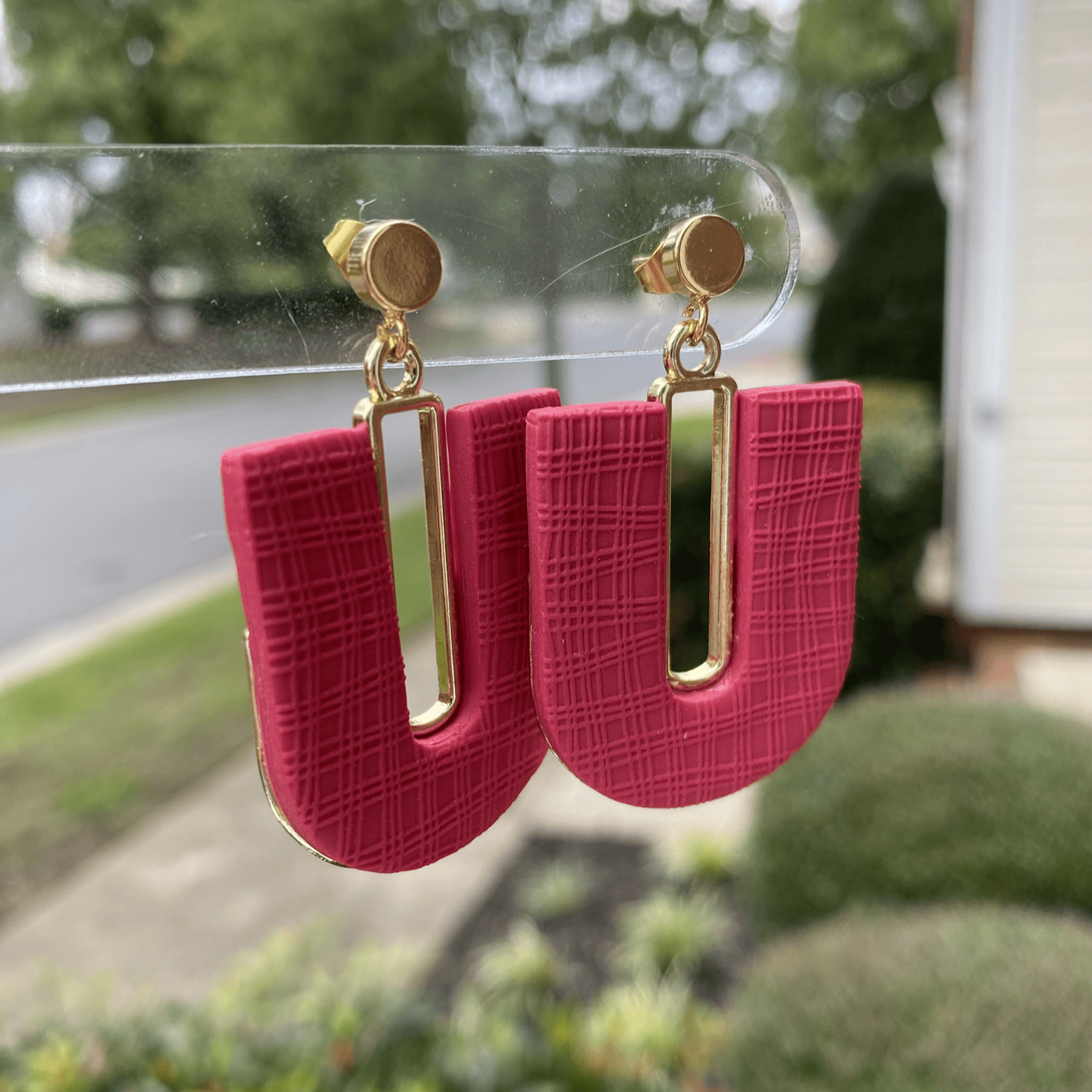Dark strawberry red textured polymer clay arch earrings with gold-plated open rectangle accents, hanging display.