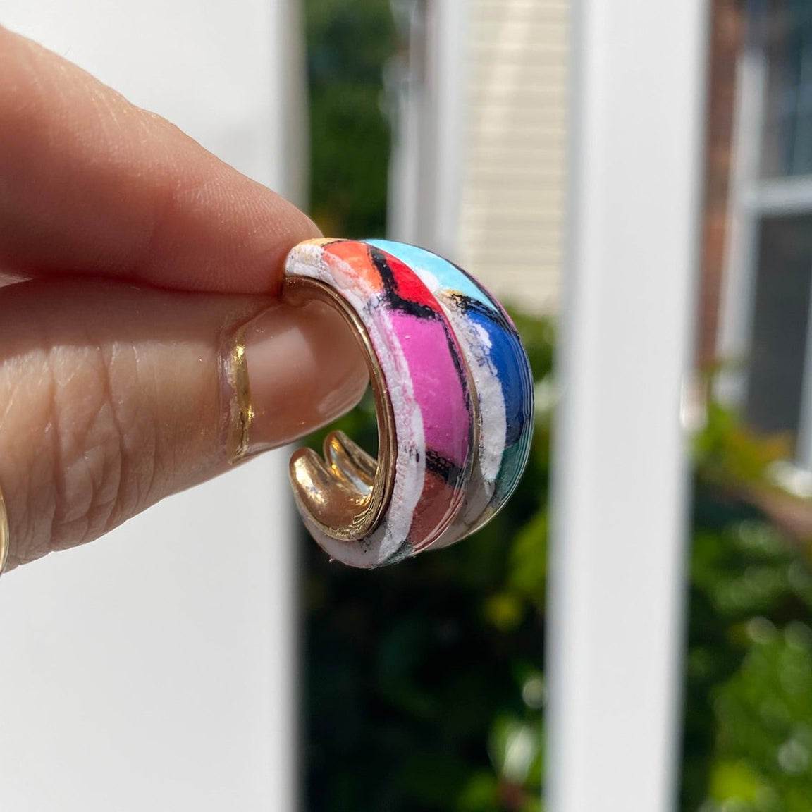 Hand-painted polymer clay stained glass mosaic hoop earring held in hand showing multicolor stripe detail, handmade in Charlotte NC by Wendy Varner Designs
