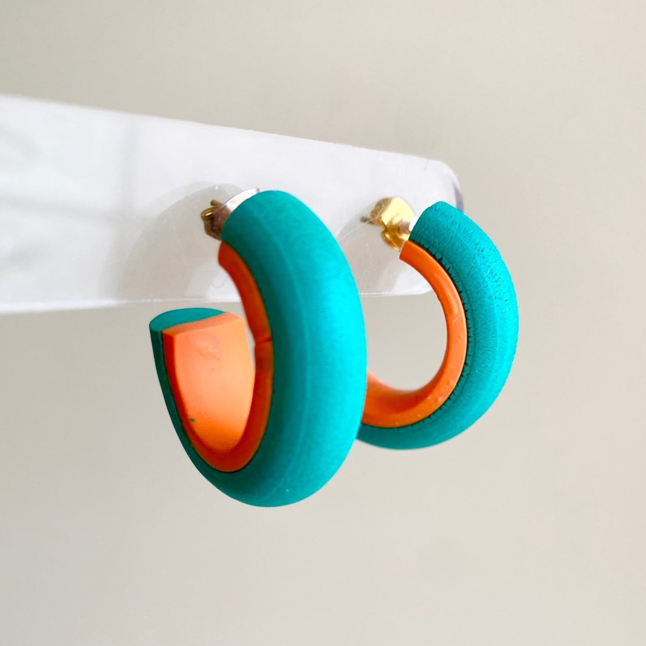 Teal and orange hoop earrings made from polymer clay, featuring a smooth, minimalist design from the Hawaiian Paradise collection.