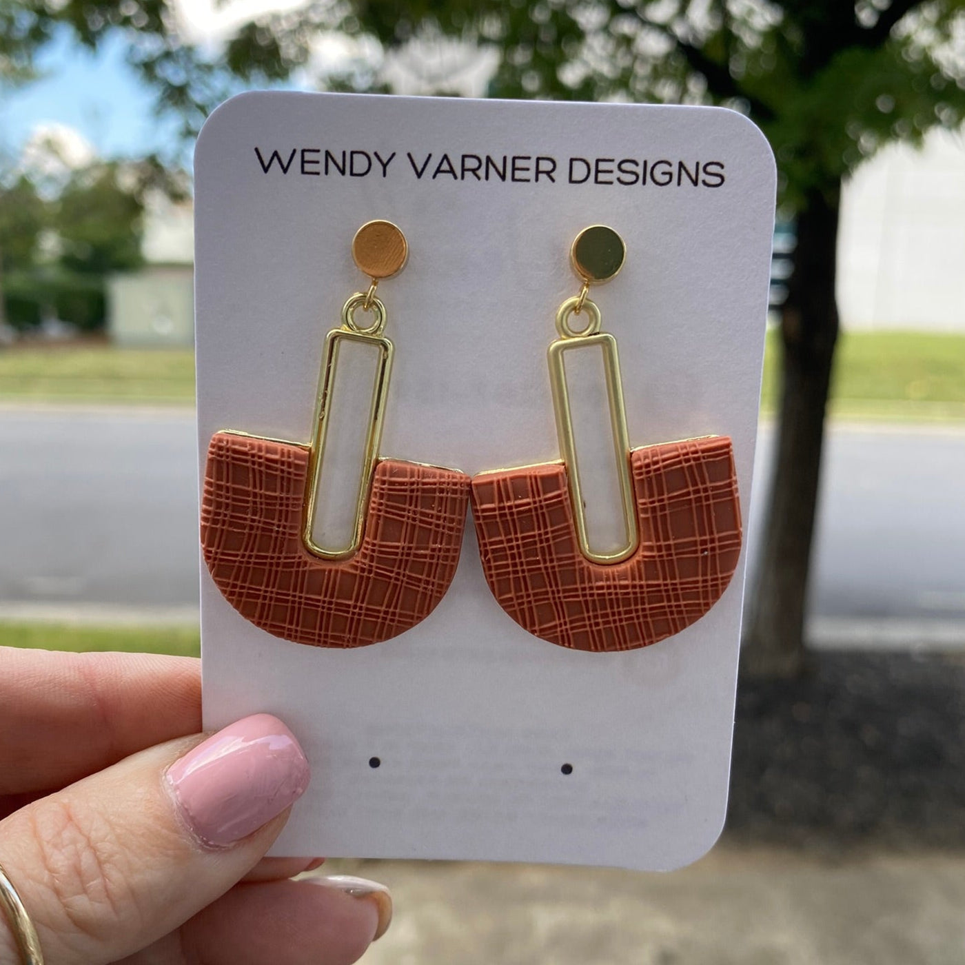 Closeup of terracotta arch polymer clay earrings with textured detail and gold rectangle