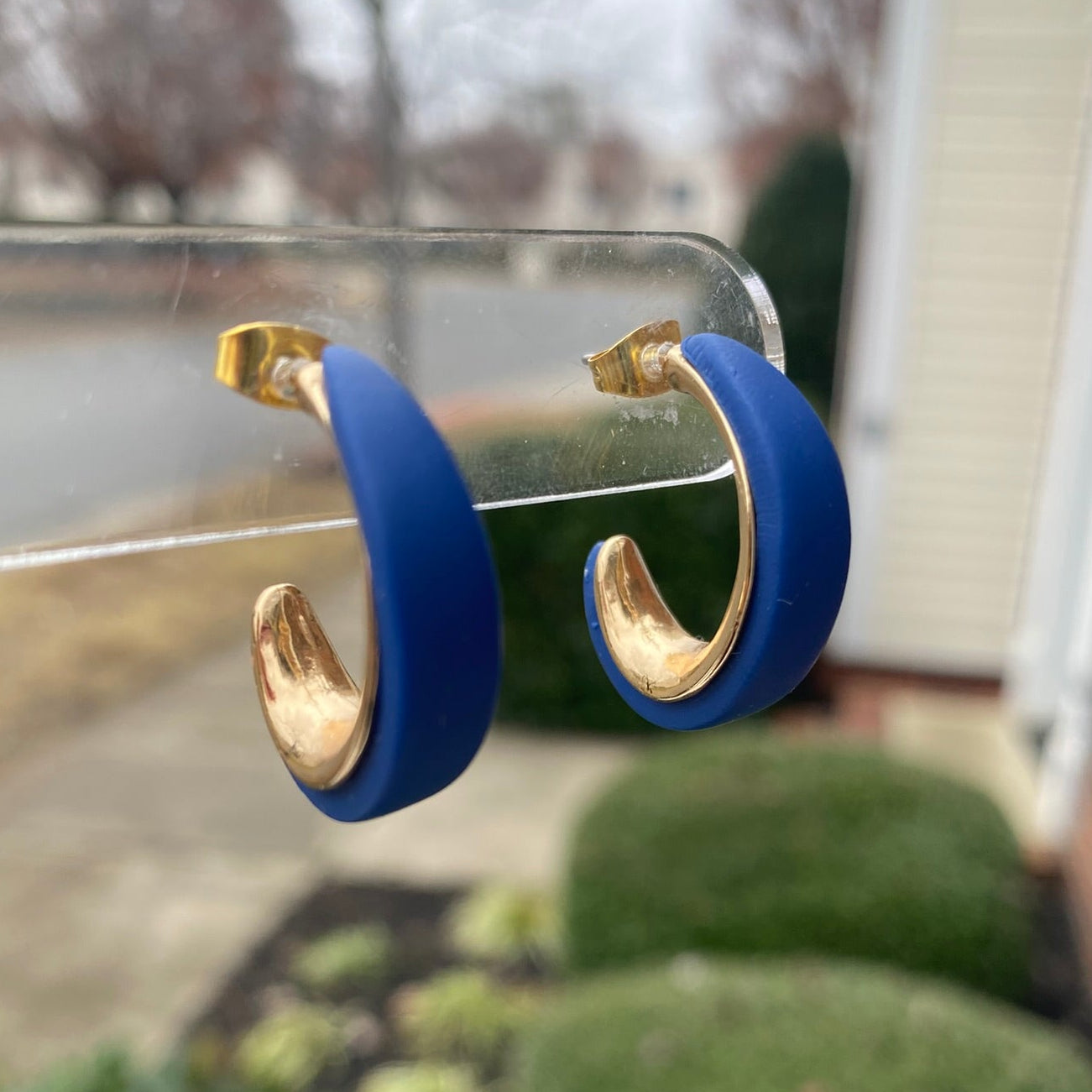 Navy Blue and gold polymer clay hoop earrings displayed outdoors on clear stand, handmade by Wendy Varner Designs 