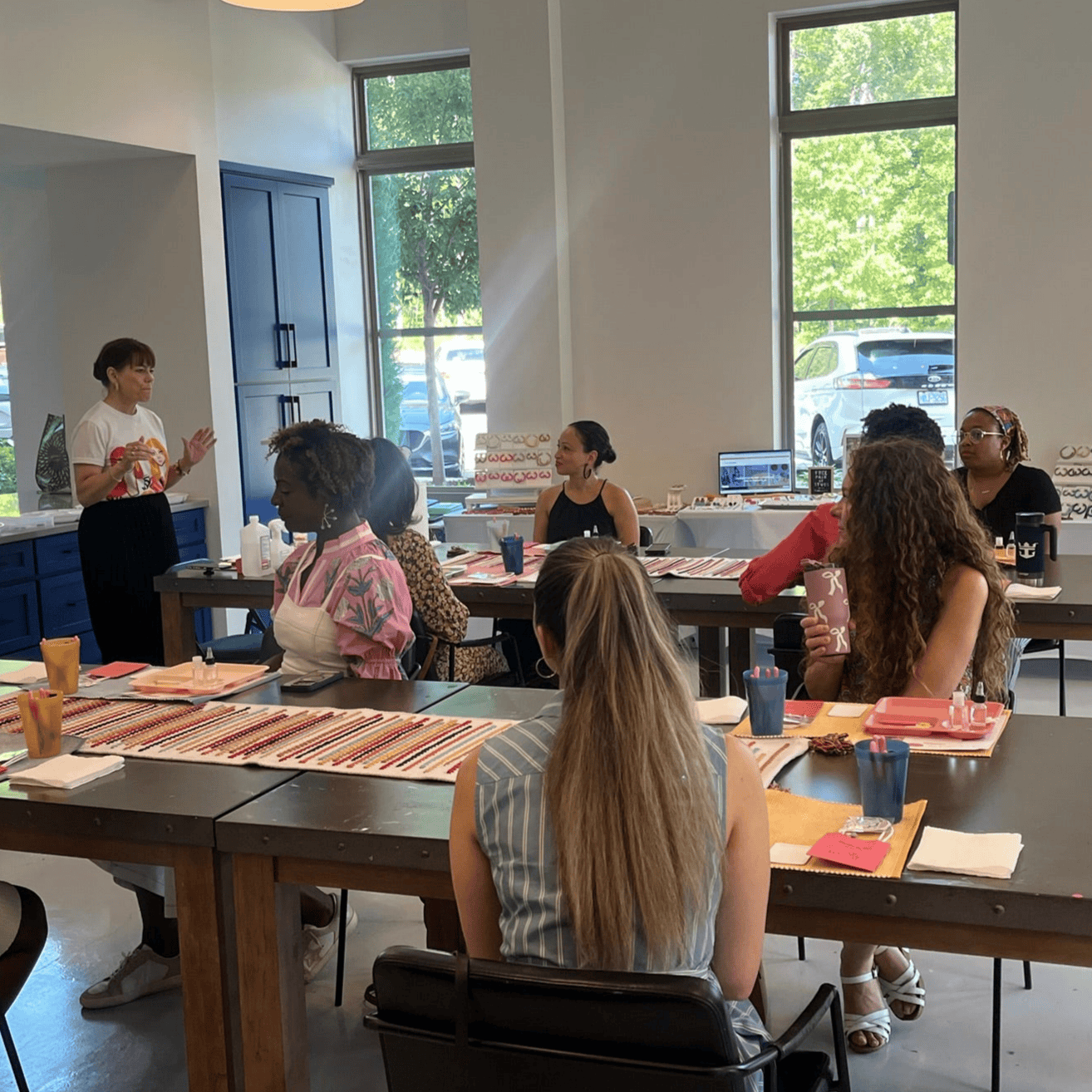 Workshop instructor demonstrating earring assembly at a clay earring workshop, with tools and materials on the table.