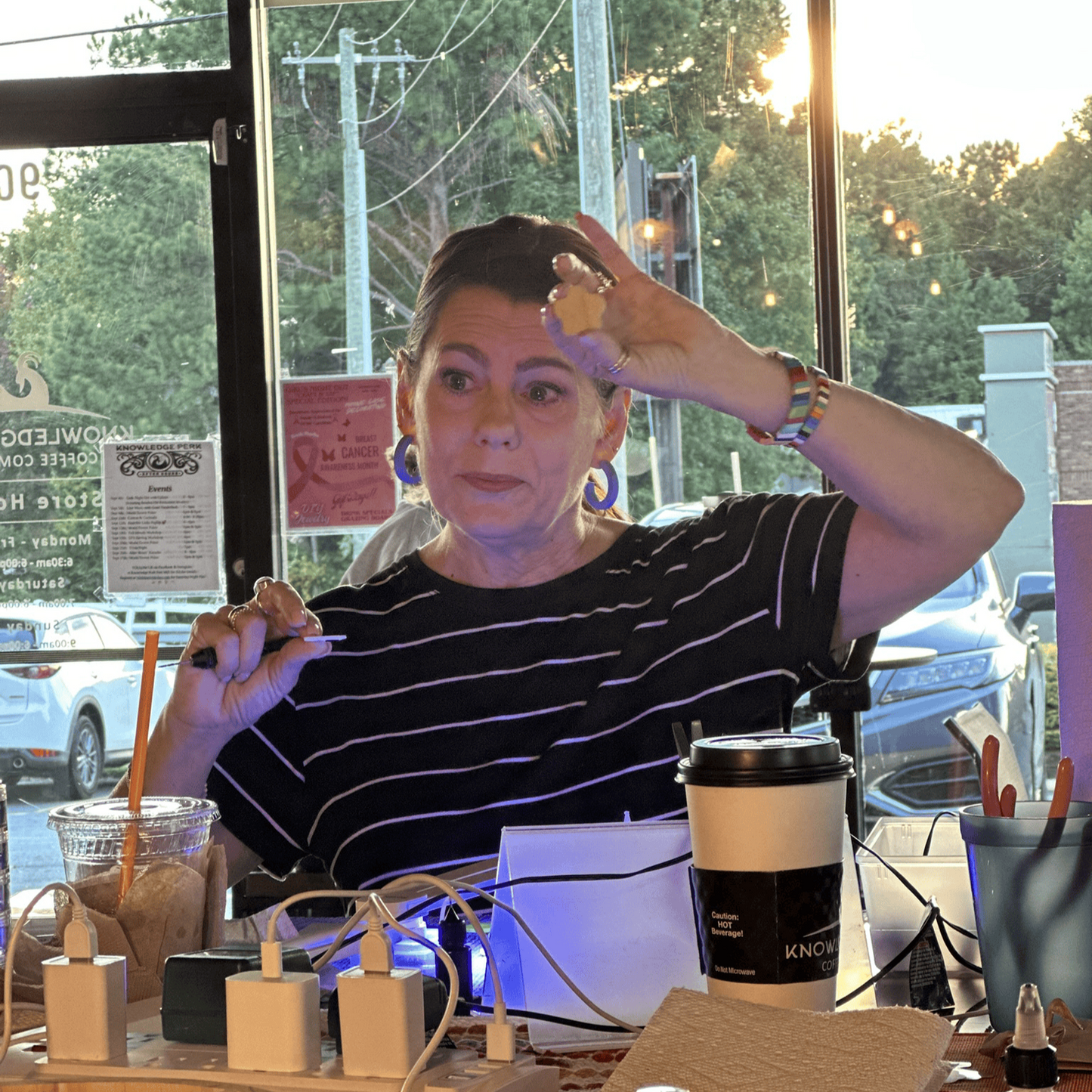 Workshop instructor demonstrating earring assembly at a clay earring workshop, with tools and materials on the table.