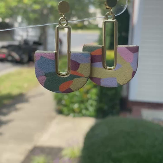 Colorful hand-painted arch earrings with gold detail photographed in natural outdoor light
