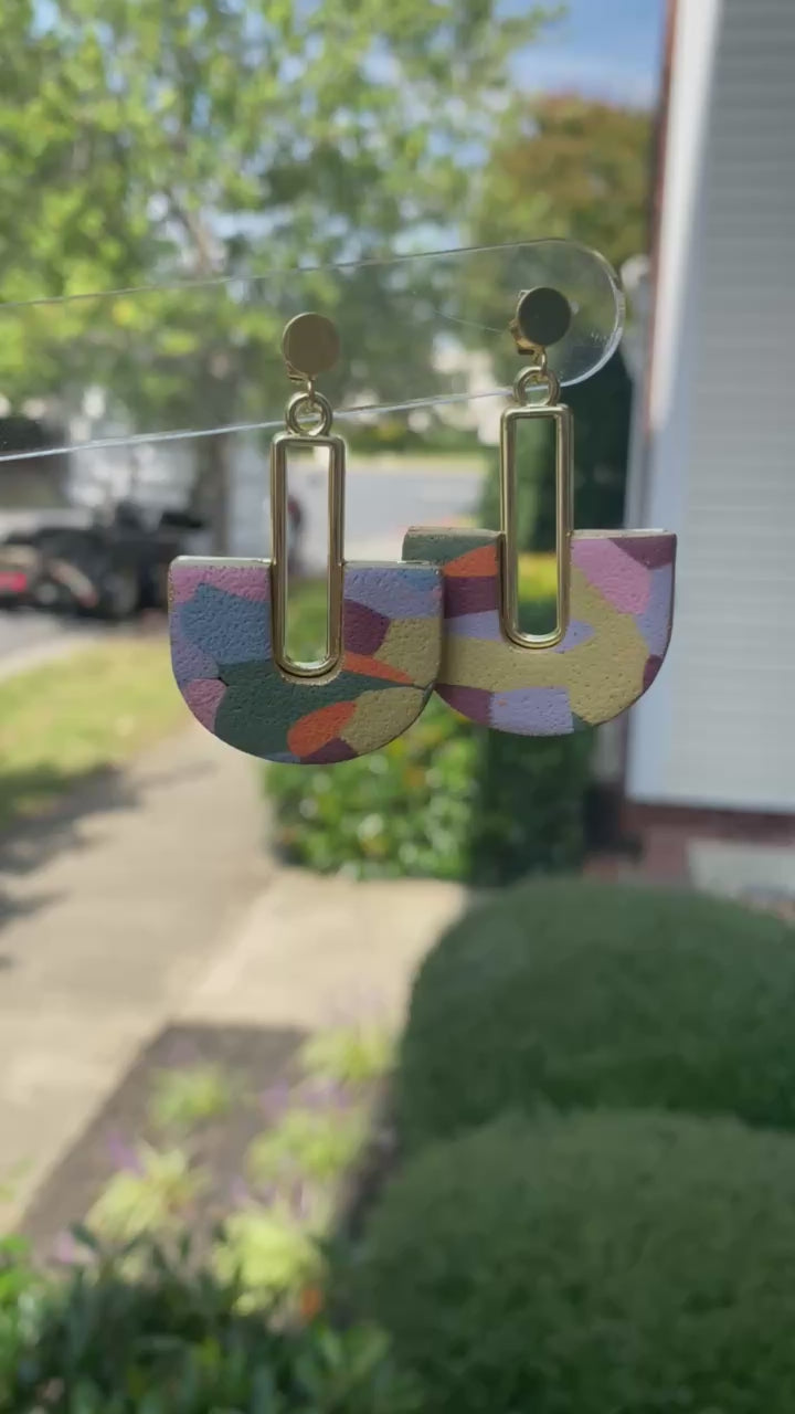 Colorful hand-painted arch earrings with gold detail photographed in natural outdoor light