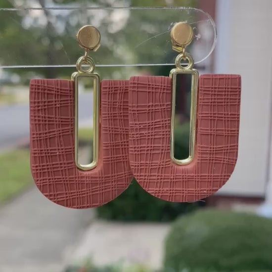Close-up of textured terracotta arch polymer clay earrings with gold-plated accents