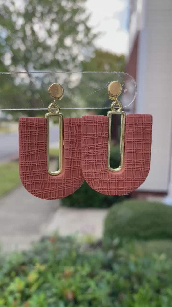 Close-up of textured terracotta arch polymer clay earrings with gold-plated accents
