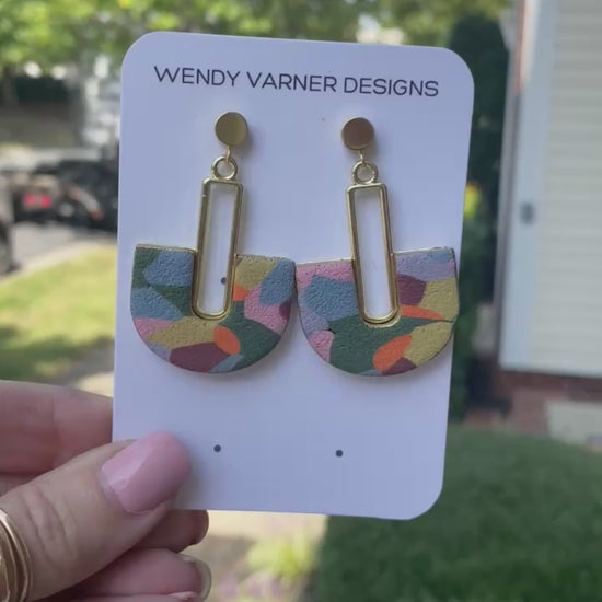 Colorful hand-painted arch earrings with gold detail photographed in natural outdoor light
