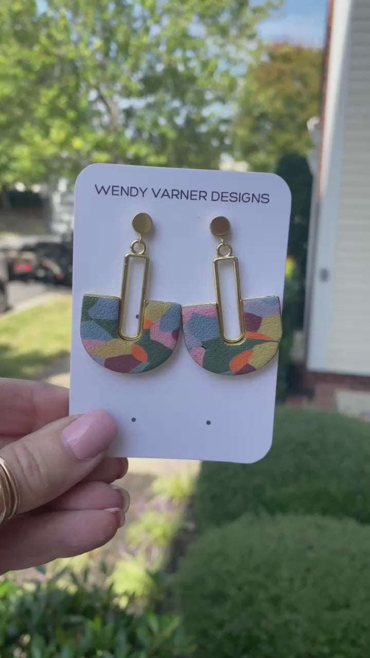 Colorful hand-painted arch earrings with gold detail photographed in natural outdoor light