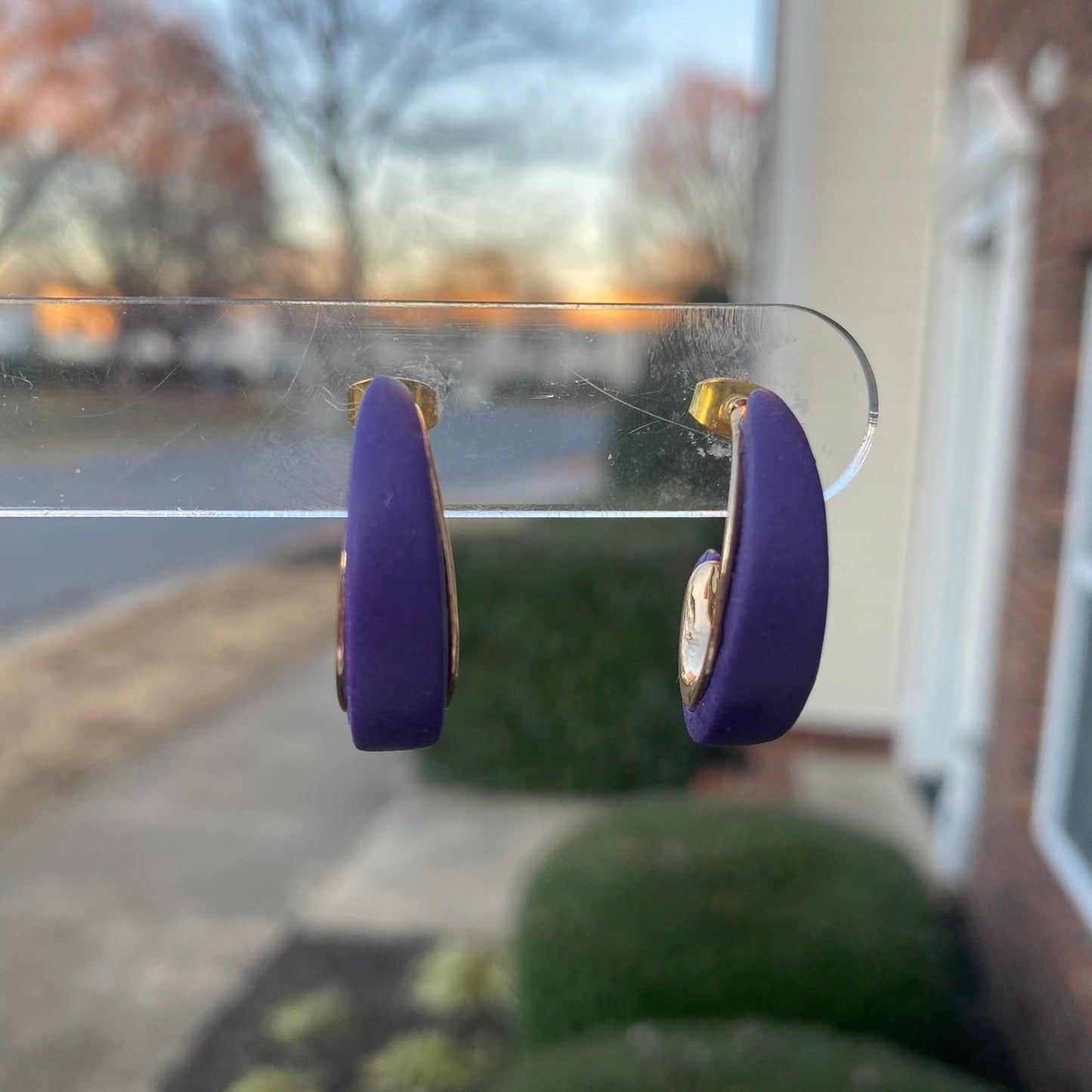 Purple and gold polymer clay hoop earrings displayed outdoors on clear stand, handmade by Wendy Varner Designs 