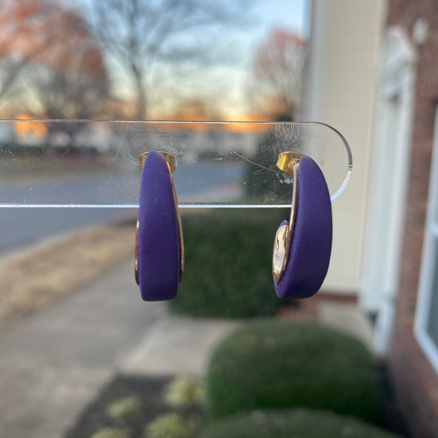 Purple and gold polymer clay hoop earrings displayed outdoors on clear stand, handmade by Wendy Varner Designs 