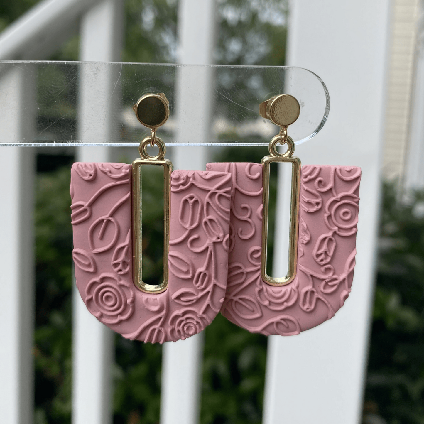 Rose blush textured polymer clay arch earrings with gold-plated open rectangle accents, hanging display.