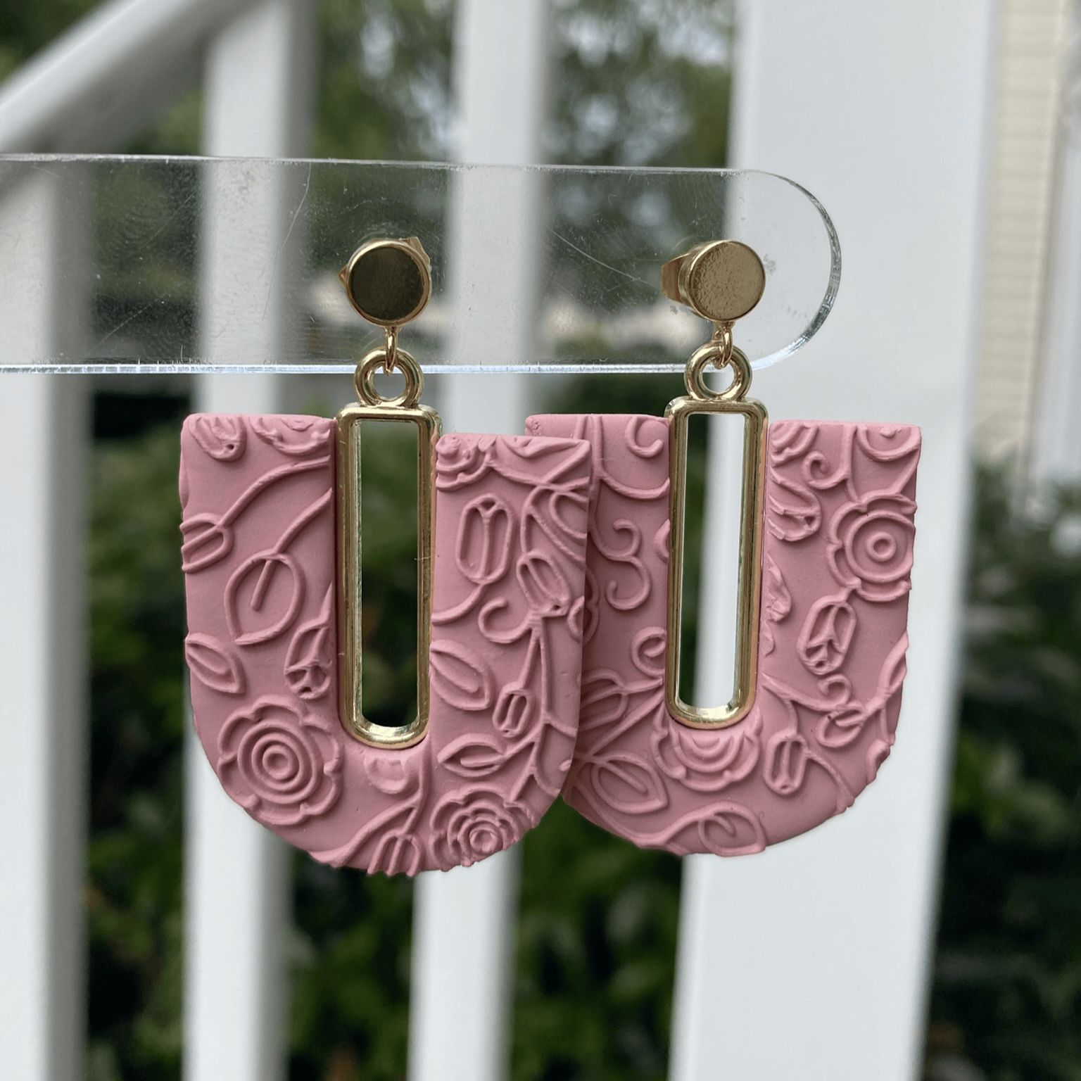 Rose blush textured polymer clay arch earrings with gold-plated open rectangle accents, hanging display.