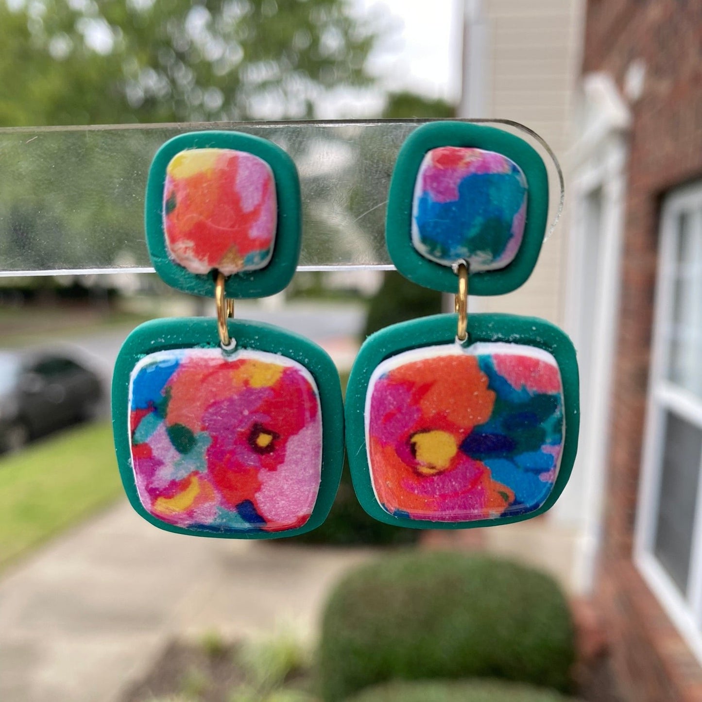 Square polymer clay earrings with vibrant, watercolor-style floral designs, accented with teal frames, from the Hawaiian Paradise collection.