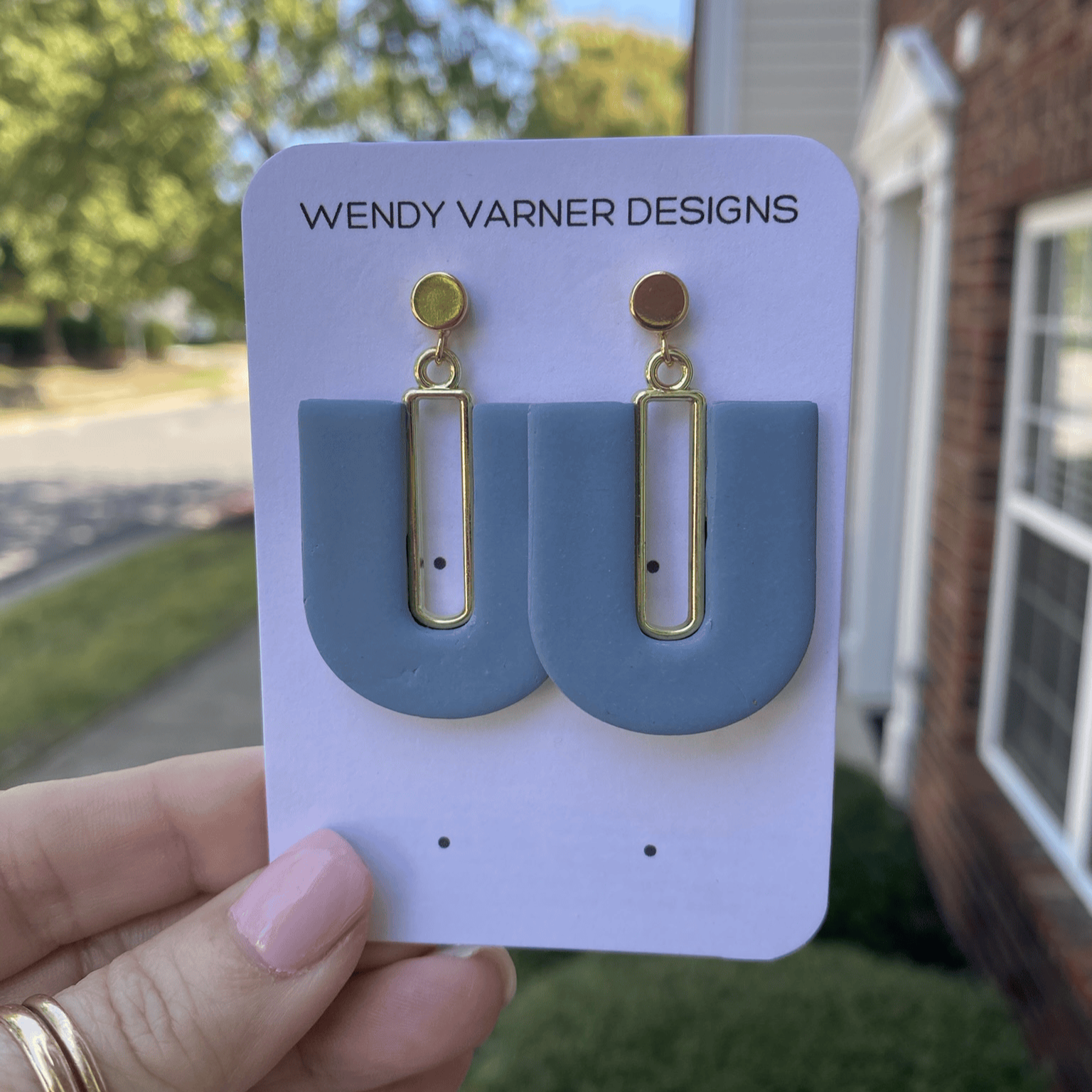 Handmade steel blue U-arch earrings with gold details in natural light