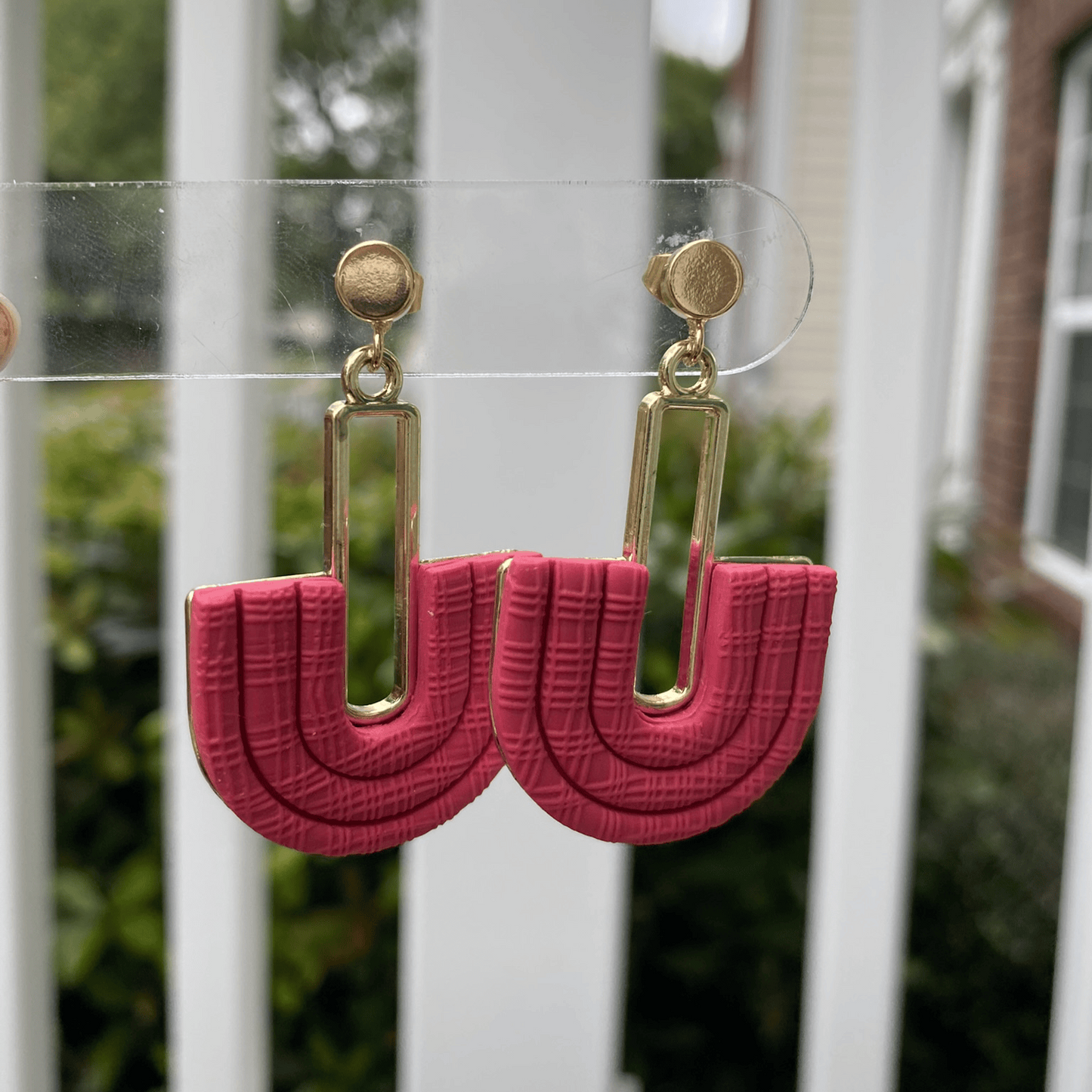 Angled view of Strawberry Red half-arch polymer clay earrings showing textured detail and gold-plated connector.