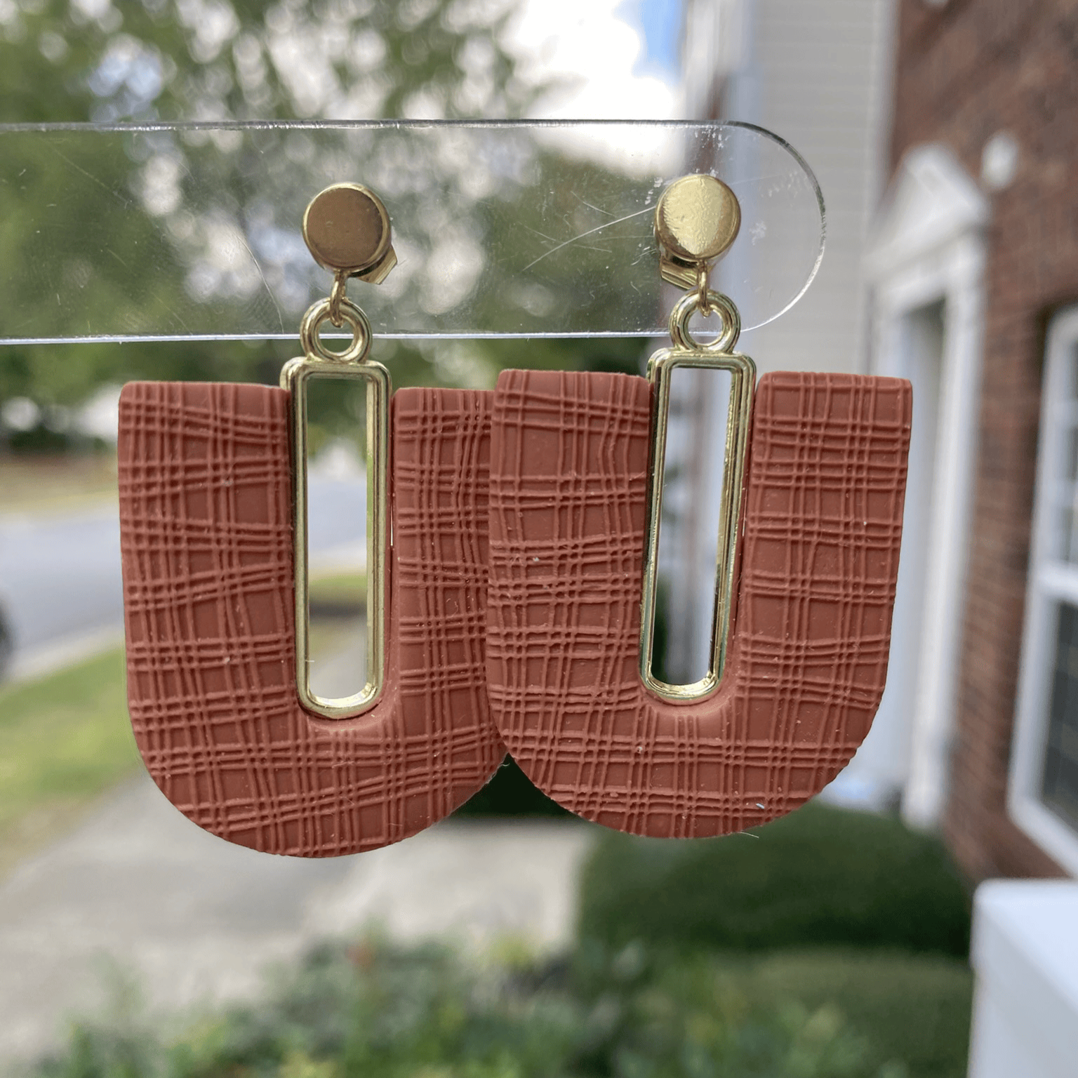 Close-up of textured terracotta arch polymer clay earrings with gold-plated accents
