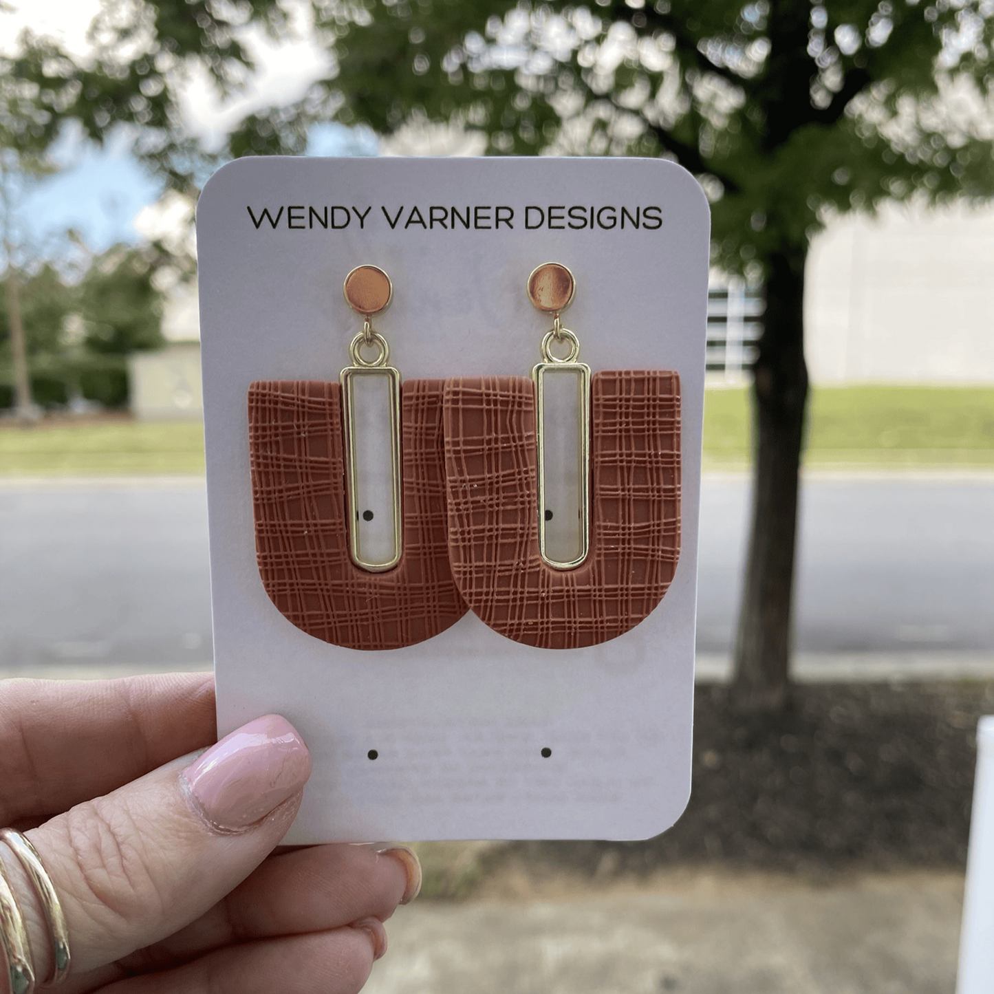 Polymer clay terra cotta arch earrings displayed outdoors in hand by Wendy Varner Designs